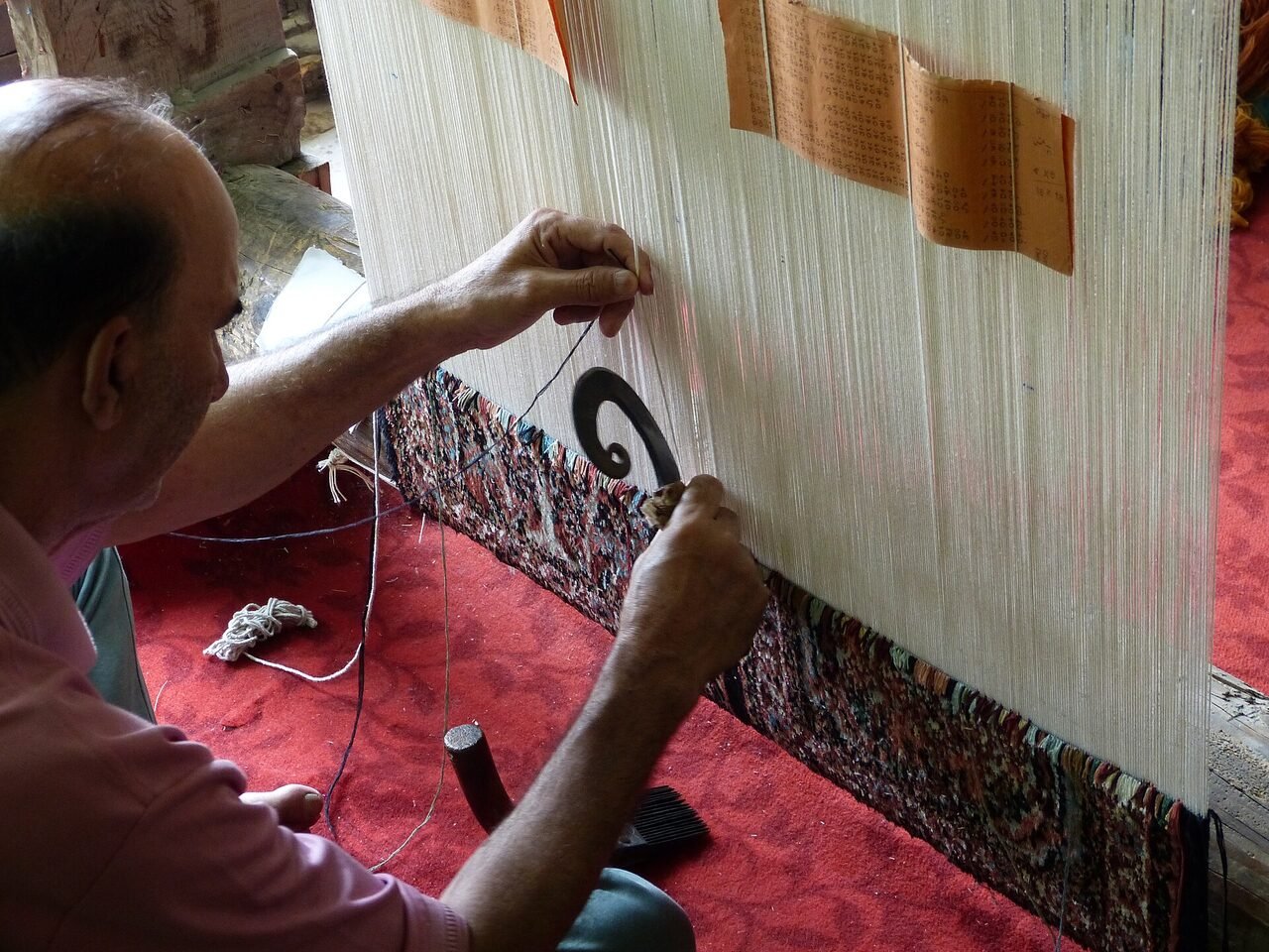A craftsman knotting a Kashmiri carpet at a traditional loom