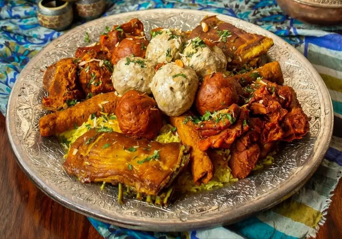 A copper trami of wazwan with rice in the centre and several meat dishes around it