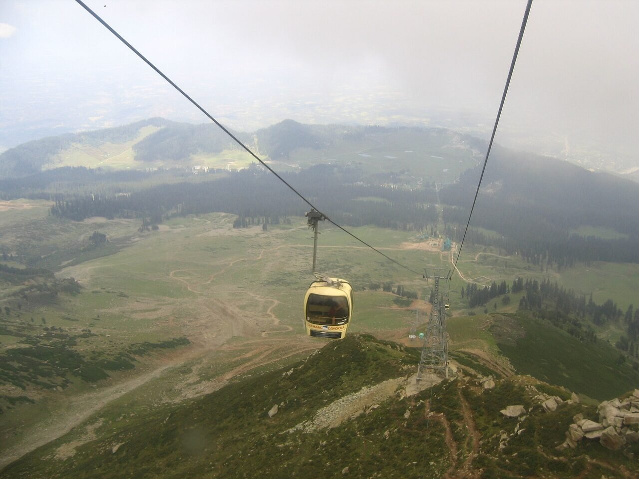Green Kashmir ridges seen from above, with cloud sitting in the valleys