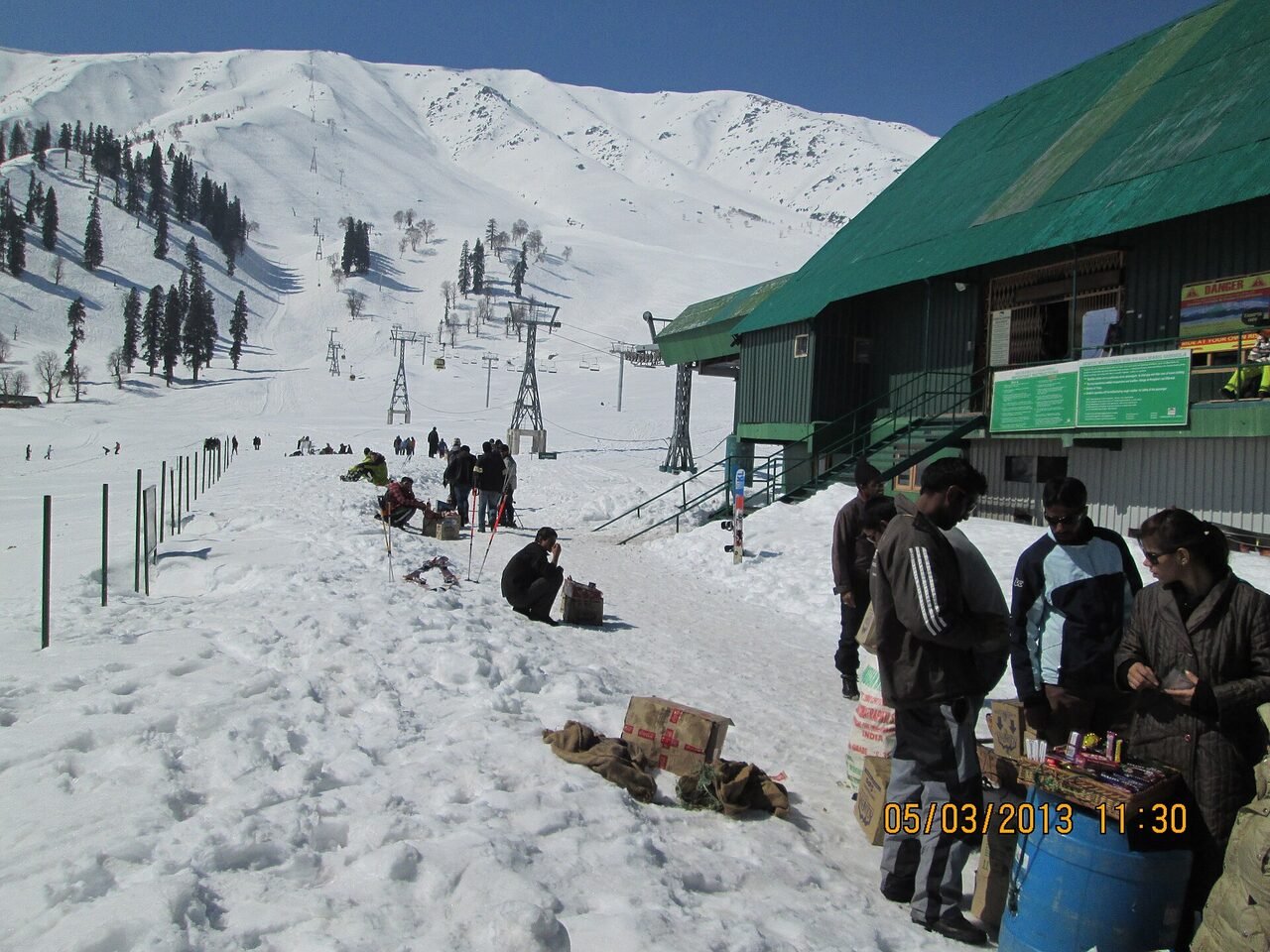 Ski tracks on a wide snow slope at Gulmarg with pines along the ridge